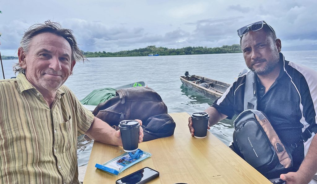 Two men in a partnership meeting with a view of the ocean behind