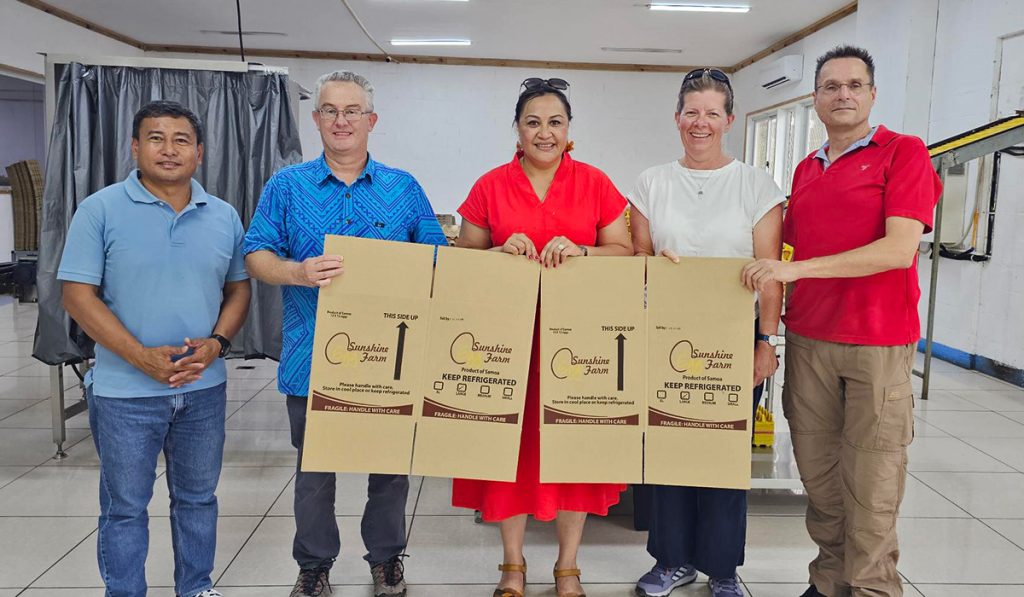 Team holding up packaging in the egg-packing room